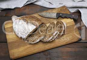 sliced bread with rye flour flour on a brown wooden board
