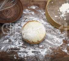 yeast dough in a wooden bowl and a round vintage sieve