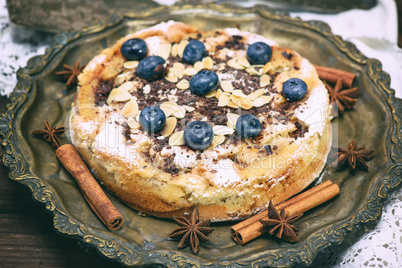 baked round cake with blueberry berries on a copper plate