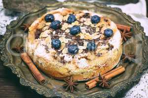 baked round cake with blueberry berries on a copper plate