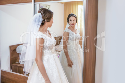 Bride in white dress looking in the mirror
