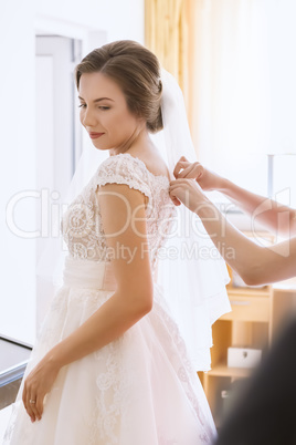 Beautiful young bride in wedding dress in living room