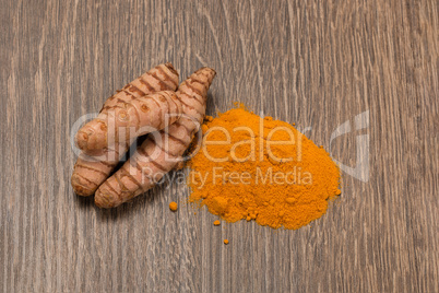 turmeric powder with turmeric root over wood