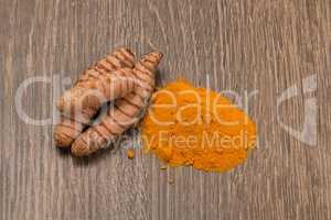 turmeric powder with turmeric root over wood