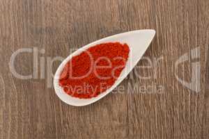 Red pepper powder over wood background