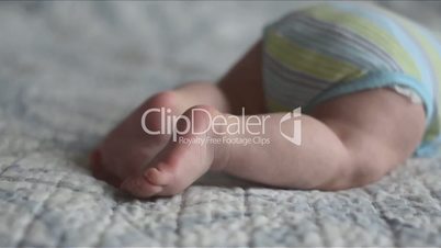 closeup of baby's feet trying to crawl lying on the bed