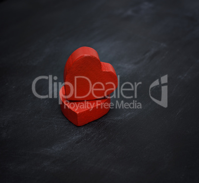 two red wooden hearts on a black background