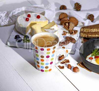 coffee with brown foam in a white ceramic mug, behind a round ca