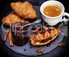 croissant with strawberry jam and white cup with coffee