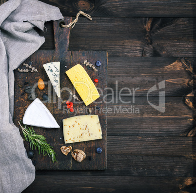 cheeses on a brown wooden board: brie, roquefort