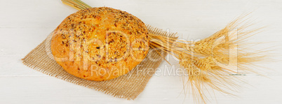 Fresh bread and wheat on the wooden table. Wide photo.