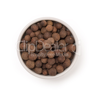seeds of allspice in a white bowl on a white background