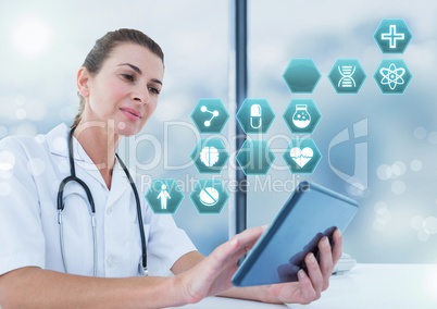 Female doctor holding tablet with medical interface hexagon icons