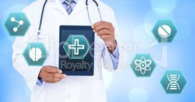 Male doctor holding tablet with medical interface hexagon icons