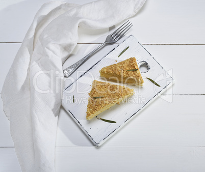 two pieces of Napoleon cake on a white wooden board