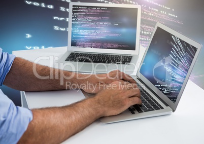 Man typing coding text on two laptops