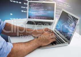 Man typing coding text on two laptops