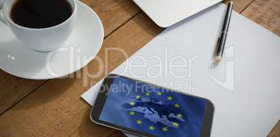 Composite image of laptop, mobile phone, black coffee, pen and paper on wooden plank