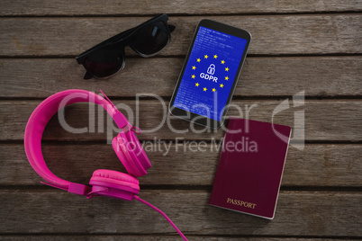 Composite image of headphones, sunglasses, passport and mobile phone wooden plank