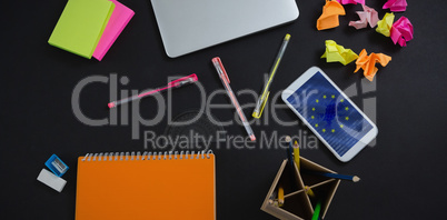 Composite image of laptop, mobile phone and stationery on black background