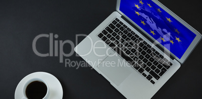 Composite image of laptop, pen and black coffee on black background
