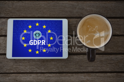 Composite image of digital tablet and cup of coffee on wooden plank