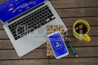 Composite image of laptop, mobile phone, dairy, pen and coffee on wooden plank