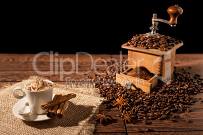 Coffee cup with whipped cream and coffee grinder