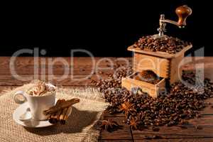 Coffee cup with whipped cream and coffee grinder