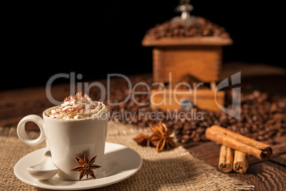 Coffee cup with whipped cream, cocoa powder and star anise