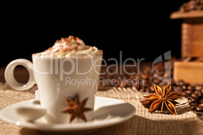 Close-up of coffee cup with whipped cream and star anise