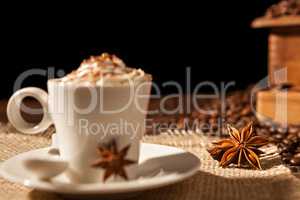 Close-up of coffee cup with whipped cream and star anise