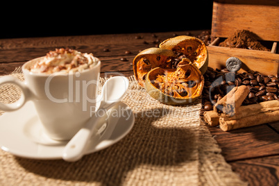 Close-up of coffee cup, dried orange fruit and cinnamon sticks