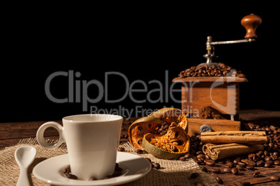 Coffee cup, dried orange fruit, cinnamon sticks and coffee grinder
