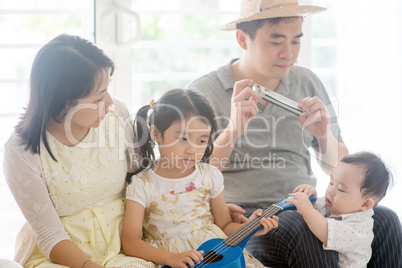 Family playing music instrument at home