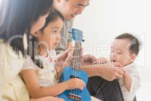 Family playing ukulele at home