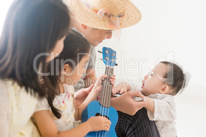 Asian family playing ukulele and harmonica at home