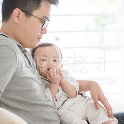 Father and baby sitting on sofa.