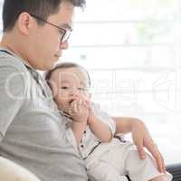 Father and baby sitting on sofa.