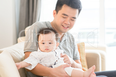 Father holding baby sitting on sofa.