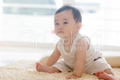 Baby boy sitting on carpet.