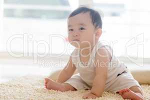 Baby boy sitting on carpet.
