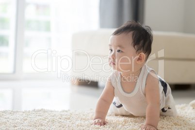 Baby boy crawling on carpet.