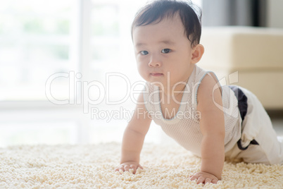 Chinese baby boy crawling on carpet.