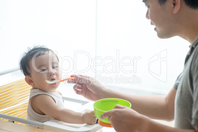 Father feeding toddler food.