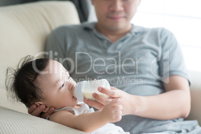 Father bottle feed milk to child.