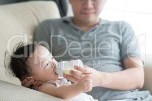 Father bottle feed milk to child.