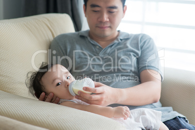 Father bottle feed milk to baby.