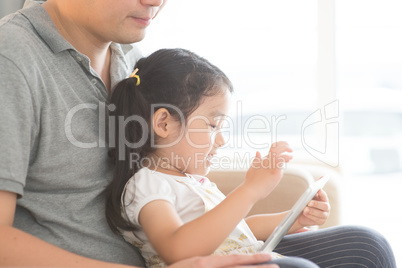 Father and daughter using digital tablet.