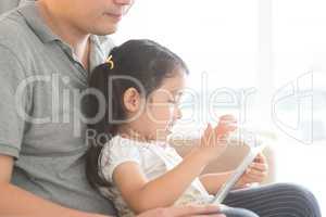 Father and daughter using digital tablet.